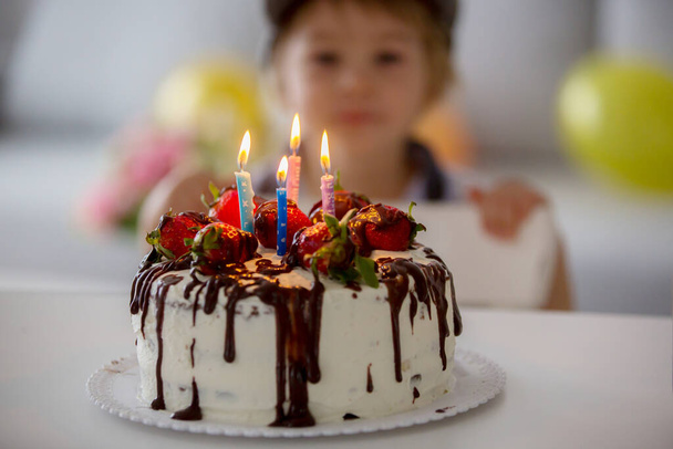 Four years old blond child, preschool boy, celebrating birthday at home with homemade cake with strawberries and chocolate - Foto, imagen