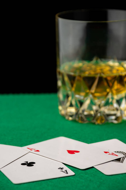Close-up of poker cards on green tablecloth with glass of whiskey, defocused, black background, vertical, with copy space - Photo, Image