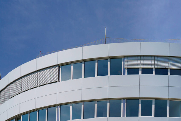 Fragmento de un edificio semicircular contra un cielo azul. Edificio de administración con paneles blancos. - Foto, imagen
