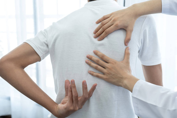 Mani mediche femminili che fanno fisioterapia estendendo la schiena di un paziente maschio. - Foto, immagini