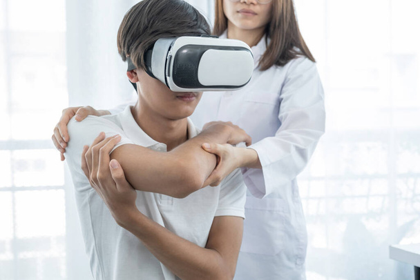 VR κουτί με ασθενή αρσενικό, Γυναίκα γιατρός κάνει φυσιοθεραπεία με την επέκταση του χεριού, η έννοια της τεχνολογίας βοήθησε το αίσθημα σαν ένας γιατρός ήρθε να θεραπεύσει στο σπίτι. - Φωτογραφία, εικόνα