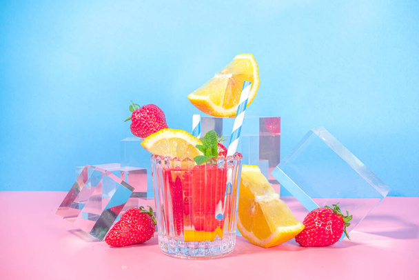 Летний яркий лимонад на красочном голубом розовом фоне со стеклянными пьедесталами подиумами со свежими фруктами, копировальное пространство  - Фото, изображение