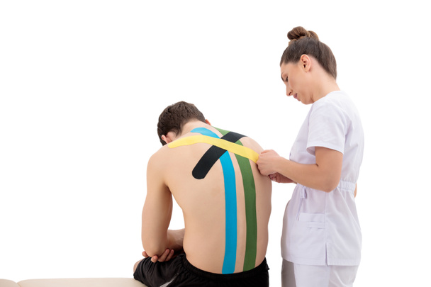 Young Woman physiotherapist Applying Special Physio Tape On Man's Back isolated on white background - Foto, imagen