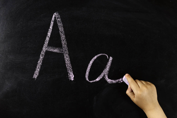 la mano del niño escribe la letra A en el tablero - Foto, Imagen