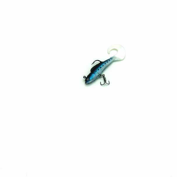 Аксессуар для рыбалки. Голубая силиконовая рыба это приманка. Два крючка, гибкий изогнутый хвост, пятна на теле. Изолированный на белом фоне. Копирование пространства - Фото, изображение