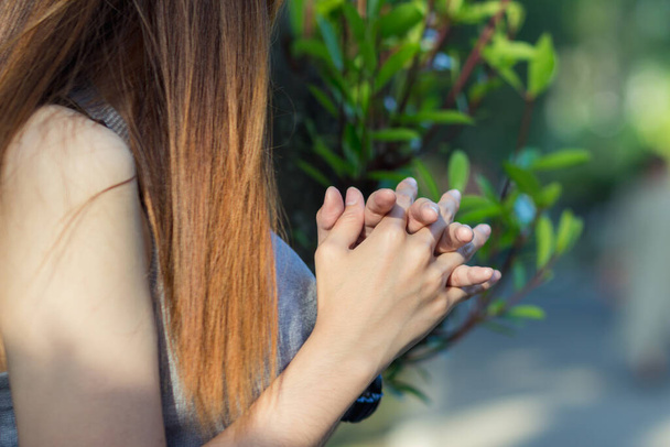 A young woman shows the symbol of prayer to God for the blessings of the Lord to find good things with faith in the sacredness and power of God on the blurred background of nature in the morning. - Photo, Image