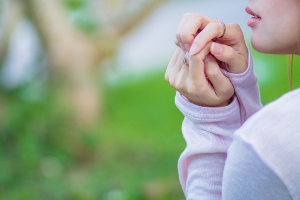 A young woman shows the symbol of prayer to God for the blessings of the Lord to find good things with faith in the sacredness and power of God on the blurred background of nature in the morning. - Photo, Image