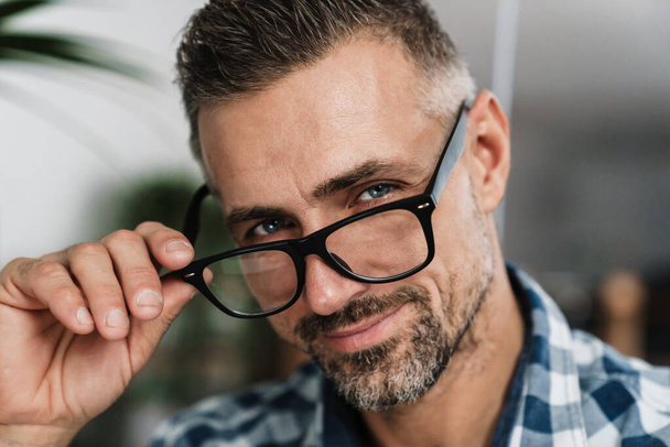 Pleased white-haired man in eyeglasses smiling and looking at camera indoors - Foto, Imagem