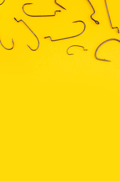 Fishing hooks on the trendy yellow backdrop. Flat lay, copy space. Fishing concept with worm hook. - Photo, Image