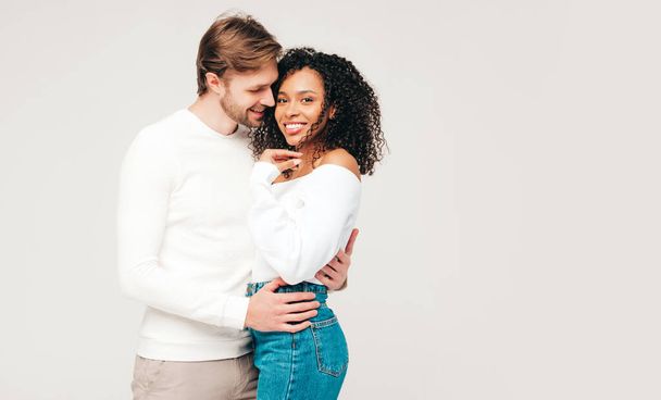 Smiling beautiful woman and her handsome boyfriend. Happy cheerful multiracial family having tender moments on grey background  in studio. Multiethnic models hugging. Embracing each other.Love concept - Foto, afbeelding