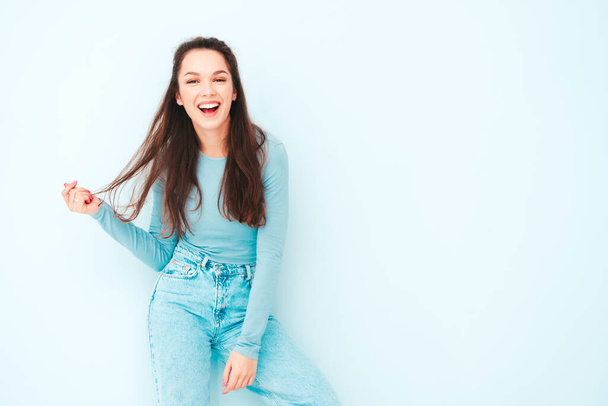Young beautiful smiling female in trendy summer hipster clothes. Sexy carefree woman posing near light blue wall in studio. Positive model having fun indoors. Cheerful and happy  - Φωτογραφία, εικόνα