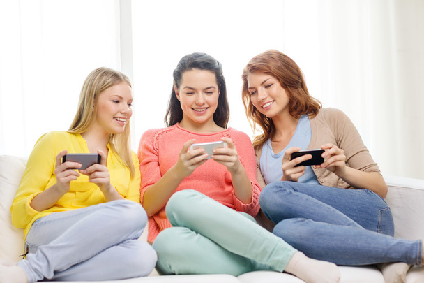 smiling teenage girls with smartphones at home - Фото, изображение