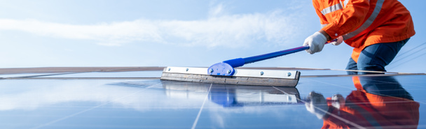 Selective focus mop of technician or worker operating use a mop cleaning solar panels at generating power of solar power plant; technician in industry uniform on level of job description at industrial - Photo, Image