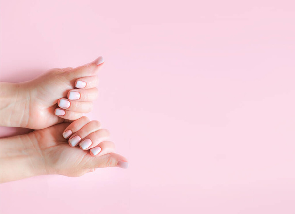 Gradient manicure and Hands Spa. Beautiful Woman hand closeup. Manicured nails and Soft hands skin. Beautiful woman's nails with beautiful baby boomer manicure, pink background. Copy space  - Foto, afbeelding