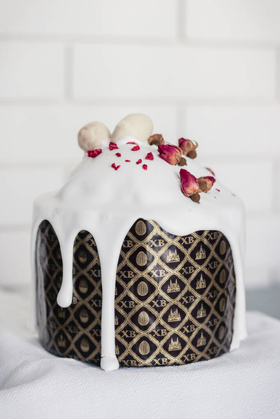 Домашний пасхальный торт украшен белой сахарной глазурью с капельницами, сушеными цветами и шоколадными яйцами - Фото, изображение