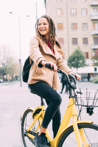 Young woman outdoors riding bike smiling - Foto, Bild