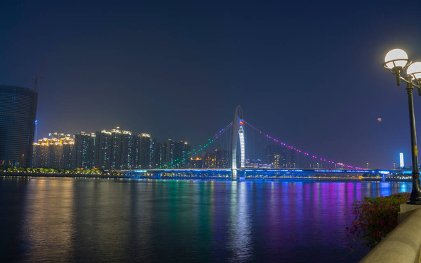 広州の街並みは珠江の上にスカイラインで、中国の広州で夜にライトアップされたLiede Bridge - 写真・画像
