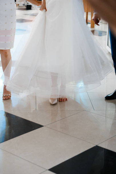 de bruid en haar vriendin lopen op de vloer, bekleed met vierkante tegels - Foto, afbeelding