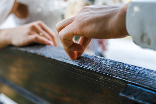 the man's fingers move along the back of the bench to the woman's hand - Photo, Image