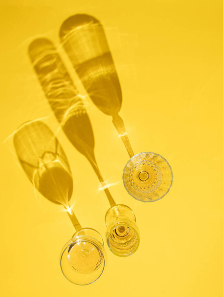 three glass of wine on yellow sunny summer background. tropical summer party creative decoration idea - Fotoğraf, Görsel