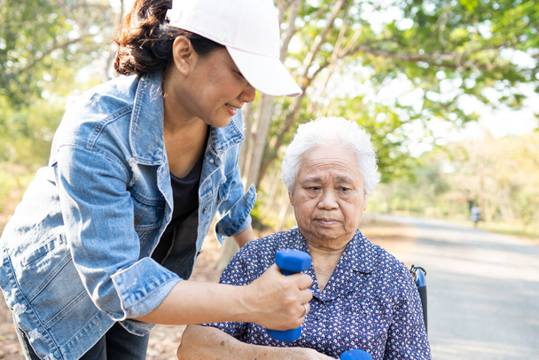 Asiatique senior ou vieille dame femme exercice avec haltère dans le parc. - Photo, image