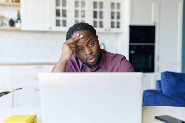 Worried African-American male freelancer using laptop for remote work from home - Foto, Imagem