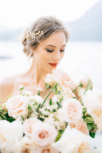 Sposa sorridente con mazzo di fiori si erge sulla riva del Lago di Como - Foto, immagini