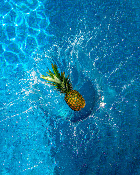 A fresh pineapple fruit falls on the water - Foto, afbeelding