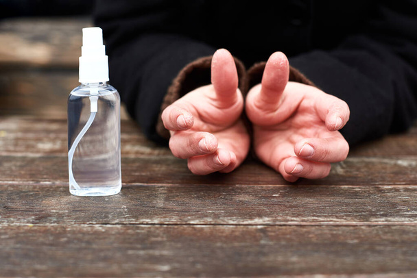 płytka głębokość dłoni z pękniętą skórą na palcach w pobliżu butelki z rozpylaczem antyseptycznym - Zdjęcie, obraz