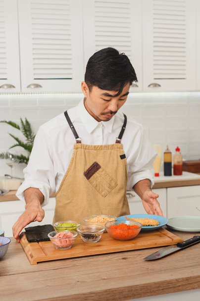 Японский повар готовит суши-роллы на белой кухне. Ингредиенты суши делают это сами - Фото, изображение