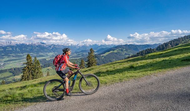 bonita mujer mayor montando su bicicleta de montaña eléctrica en las montañas sobre el valle de Iller entre Sonthofen y Oberstdorf, Alpes Allgau, Baviera Alemania - Foto, imagen