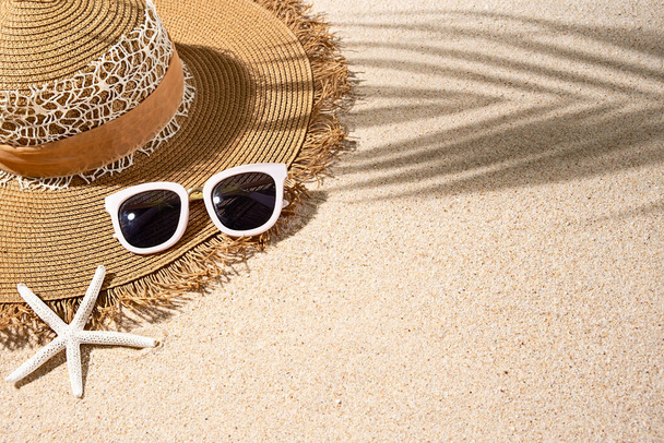 Large brown round summer heat, white sunglasses and starfish on nice beach sand, top view, copy space - Fotó, kép