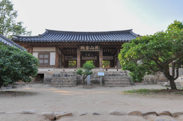 Koreaanse Confucianistische Academie uit Joseon tijdperk. Uitzicht op de grote collegezaal en de binnenplaats met bomen. Byeongsan Seowon, Andong, Zuid-Korea. Vertaling: "Byeongsan Academy, Hall of established teaching" - Foto, afbeelding