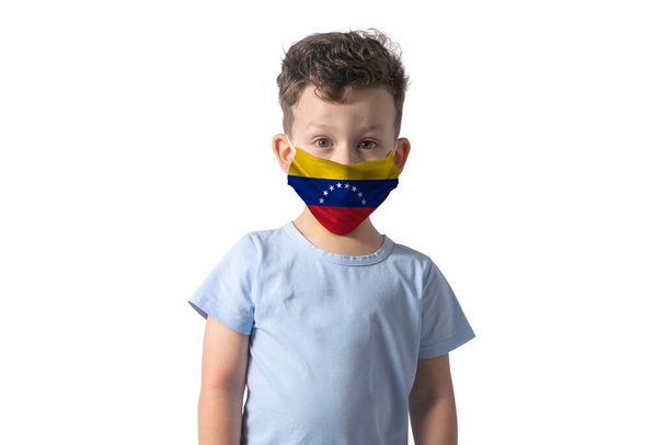 Atemschutzmaske mit Flagge Venezuelas. Weißer Junge setzt medizinische Gesichtsmaske isoliert auf weißem Hintergrund auf. - Foto, Bild
