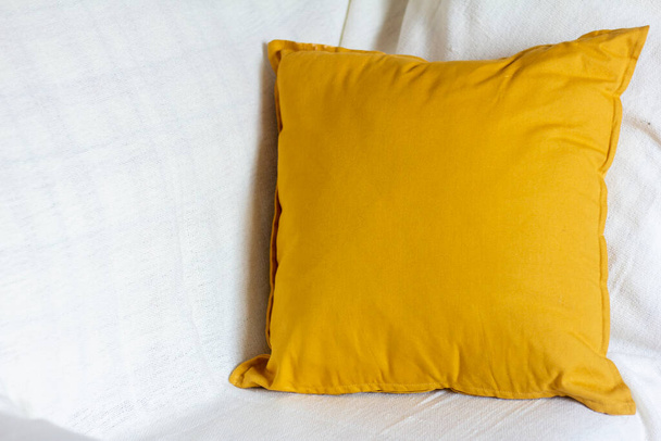 Ένα μαλακό κίτρινο ή σε χρώμα μουστάρδας μαξιλάρι σε ένα άνετο καναπέ - Φωτογραφία, εικόνα