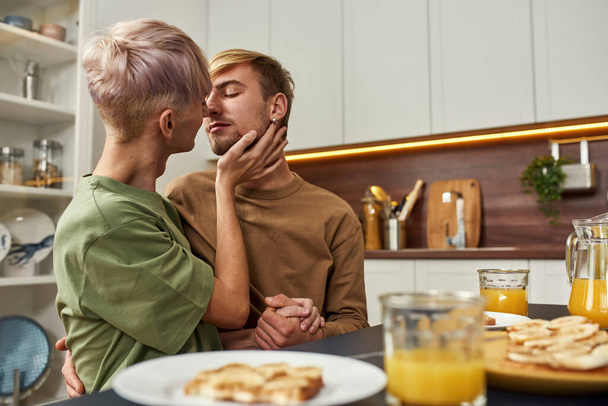 Gleichgeschlechtliches Paar bereit zum Küssen am Küchentisch - Foto, Bild