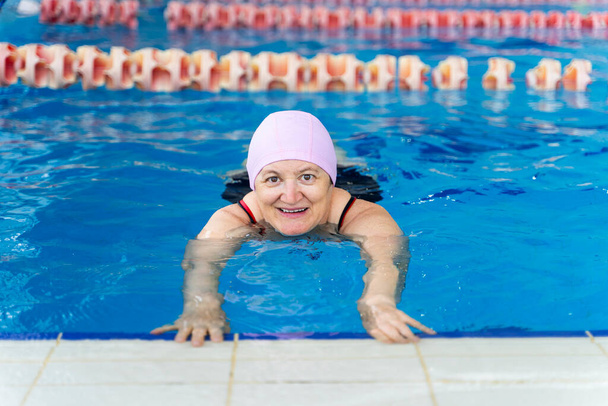 Happy middle aged woman learning to swim in a swimming pool - Foto, Imagen