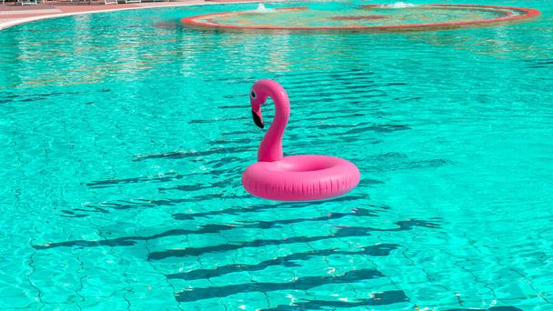 Hora de verano. Flamenco inflable rosa en el agua de la piscina para el fondo de la playa de verano. Juguete de pájaro divertido para niños - Foto, imagen
