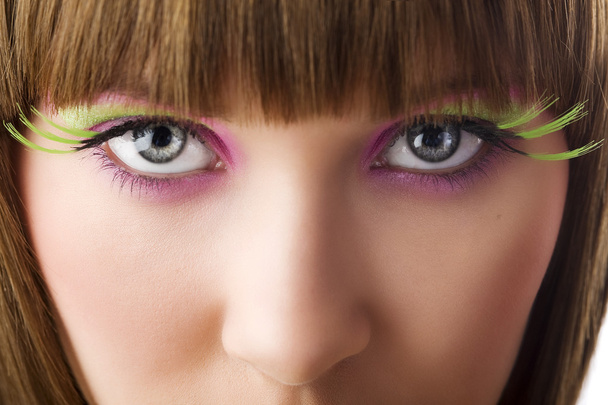 Nahaufnahme von Augen, die mit kreativem Make-up und grünen Wimpern in die Kamera blicken - Foto, Bild