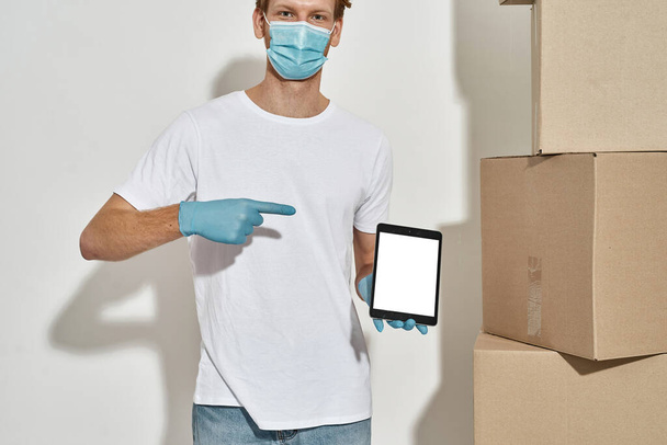 Cropped photo of a young deliveryman pointing in tablet with delivery app - Foto, Bild