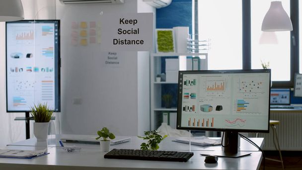 Μοντέρνο άδειο γραφείο με πλαστικούς διαχωριστές και αφίσα κοινωνικής απόστασης - Φωτογραφία, εικόνα