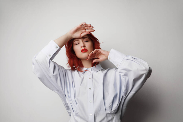 Young woman with red hair and closed eyes posing over grey background. Isolated. - Фото, зображення