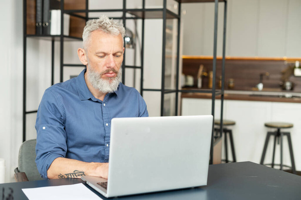 Concentrated middle age male entrepreneur using laptop for remote work - Fotoğraf, Görsel