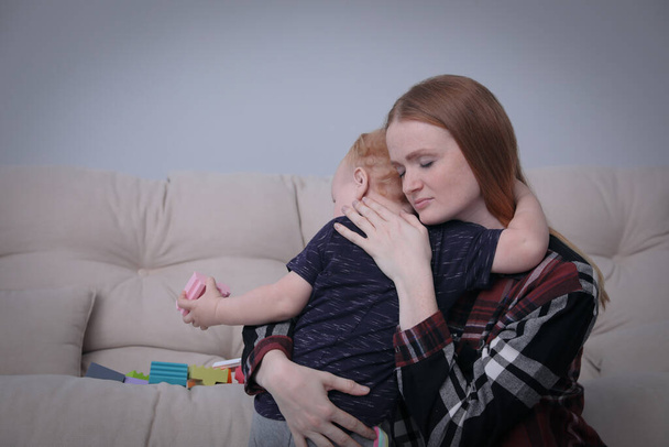 Young single mother hugging her child in living room - Foto, Imagem