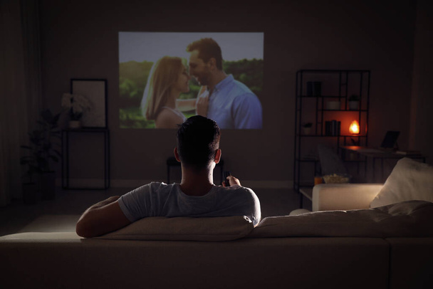 Man watching movie on sofa at night, back view - Fotó, kép