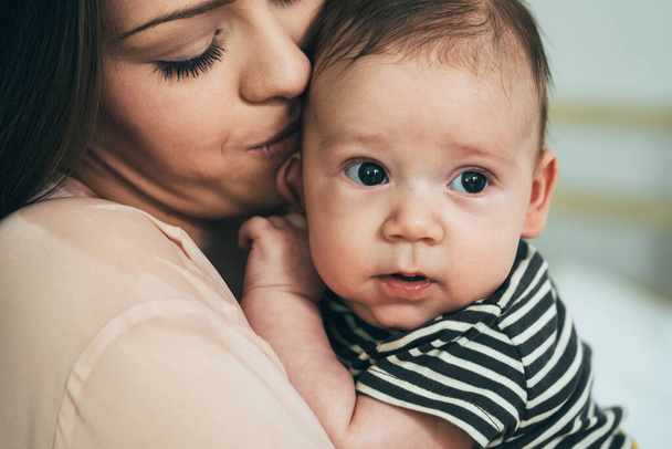 Close Up fotografie krásné matky drží její roztomilé děťátko. Pečující maminka objímající její novorozeně dítě chlapec. - Fotografie, Obrázek