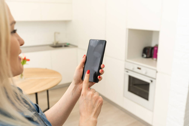 Ekranda Ev Kontrol Sistemi olan cep telefonu. Akıllı ev, ev otomasyonu, uygulama simgeli aygıt. Kadın akıllı telefonunu akıllı güvenlik uygulaması ile evinin kapısını açmak için kullanıyor. - Fotoğraf, Görsel