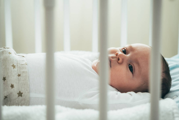 Fechar Foto de Bebê Adorável Deitado no CribAdorável menino recém-nascido deitado na cama em casa. - Foto, Imagem