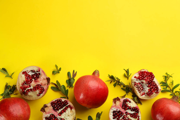 Flat lay composition with ripe pomegranates on yellow background. Space for text - Fotó, kép