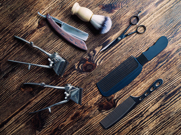 En una superficie rústica de madera envejecida son viejas herramientas de barbero. dos Vintage cortador de pelo manual peine cepillo de afeitar cepillo de afeitar tijeras de peluquería. horizontal. Vista superior, plano - Foto, Imagen